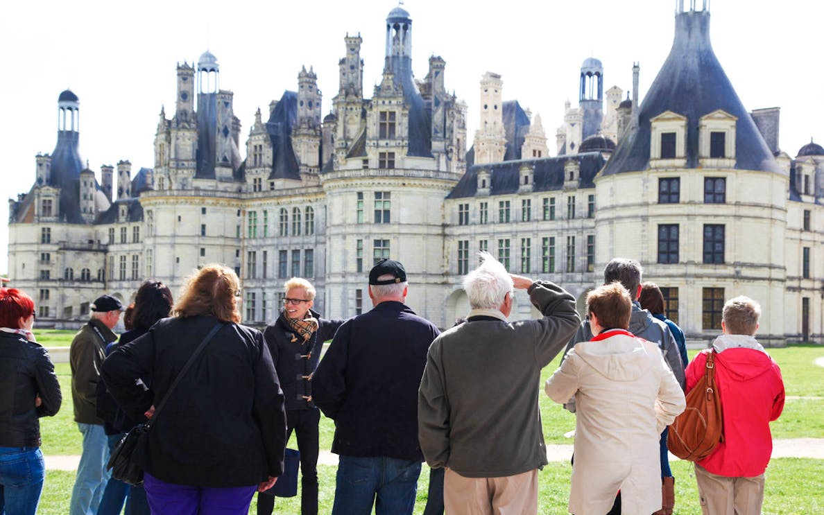 Tour group at Château de Chambord, France, with guide explaining the architecture.