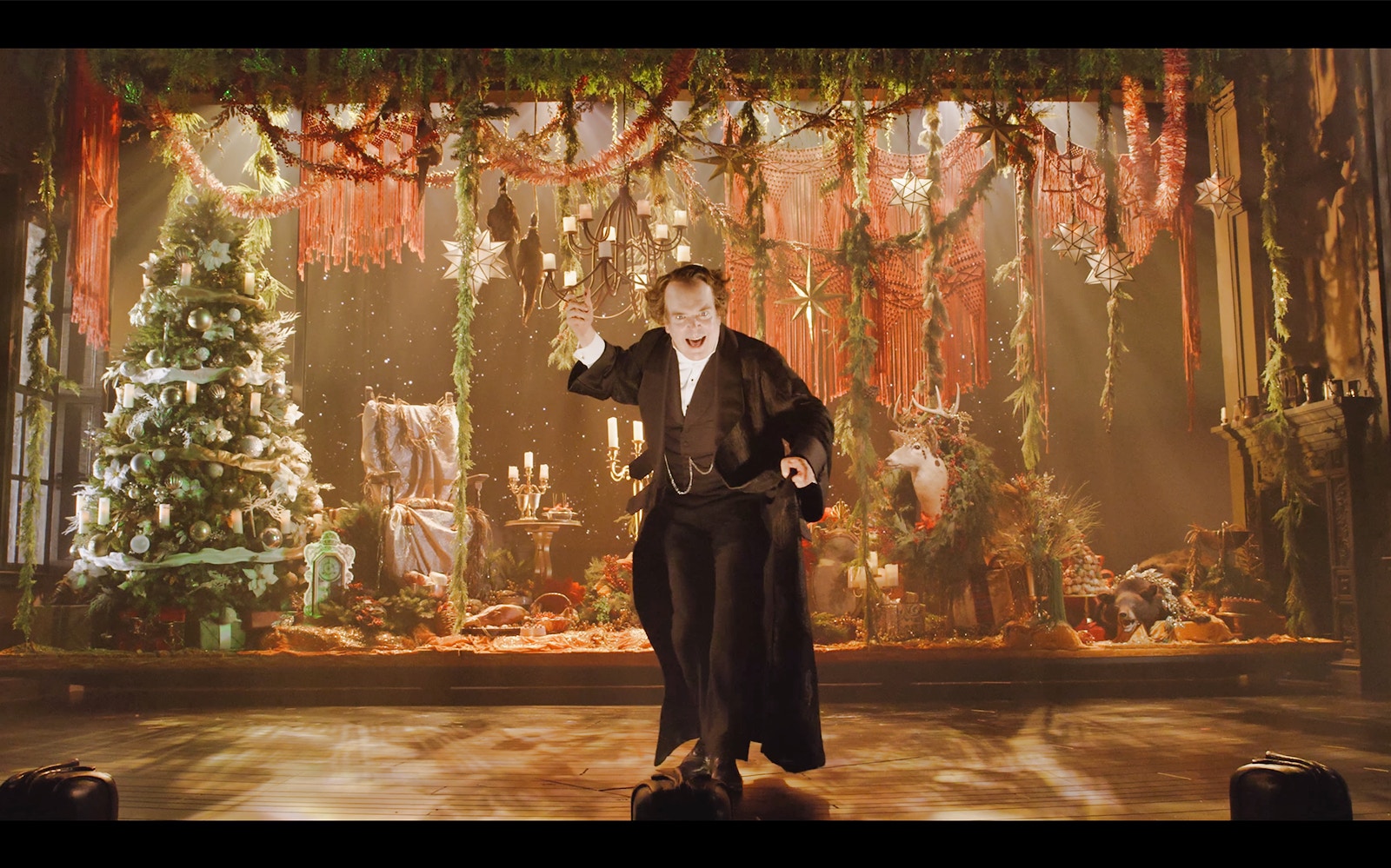 Actor performing "A Christmas Carol" on a festive stage with Christmas tree and decorations.