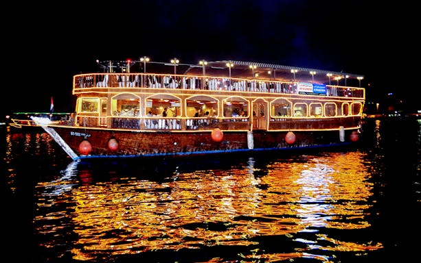 Lit dhow cruise on Dubai Creek at night, ideal for family tours.