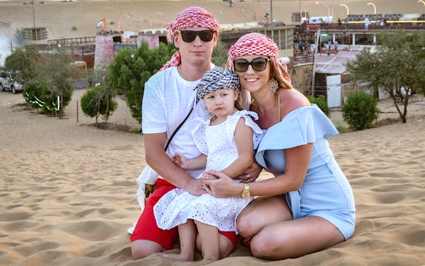 Family enjoying a desert tour in Dubai, wearing traditional headscarves.