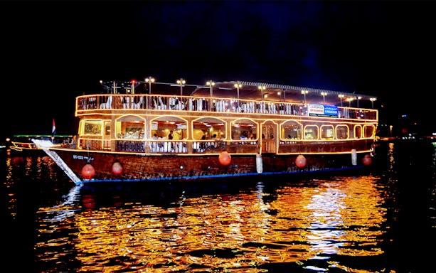 Lit dhow cruise on Dubai Creek at night for honeymoon package.