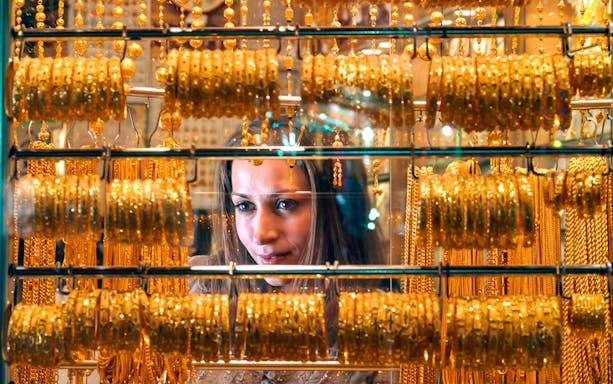 Woman admiring gold jewelry in Dubai market, part of Dubai Honeymoon Package.