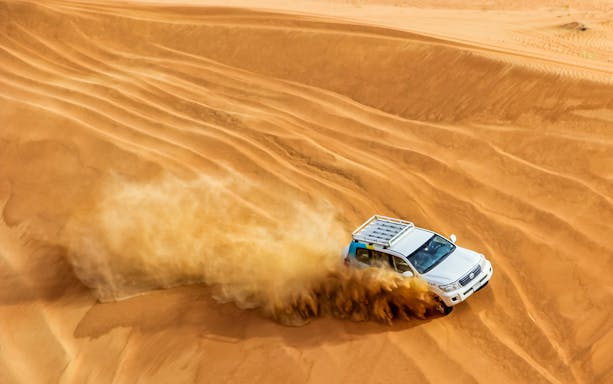 Desert safari in Dubai with SUV driving through sand dunes.