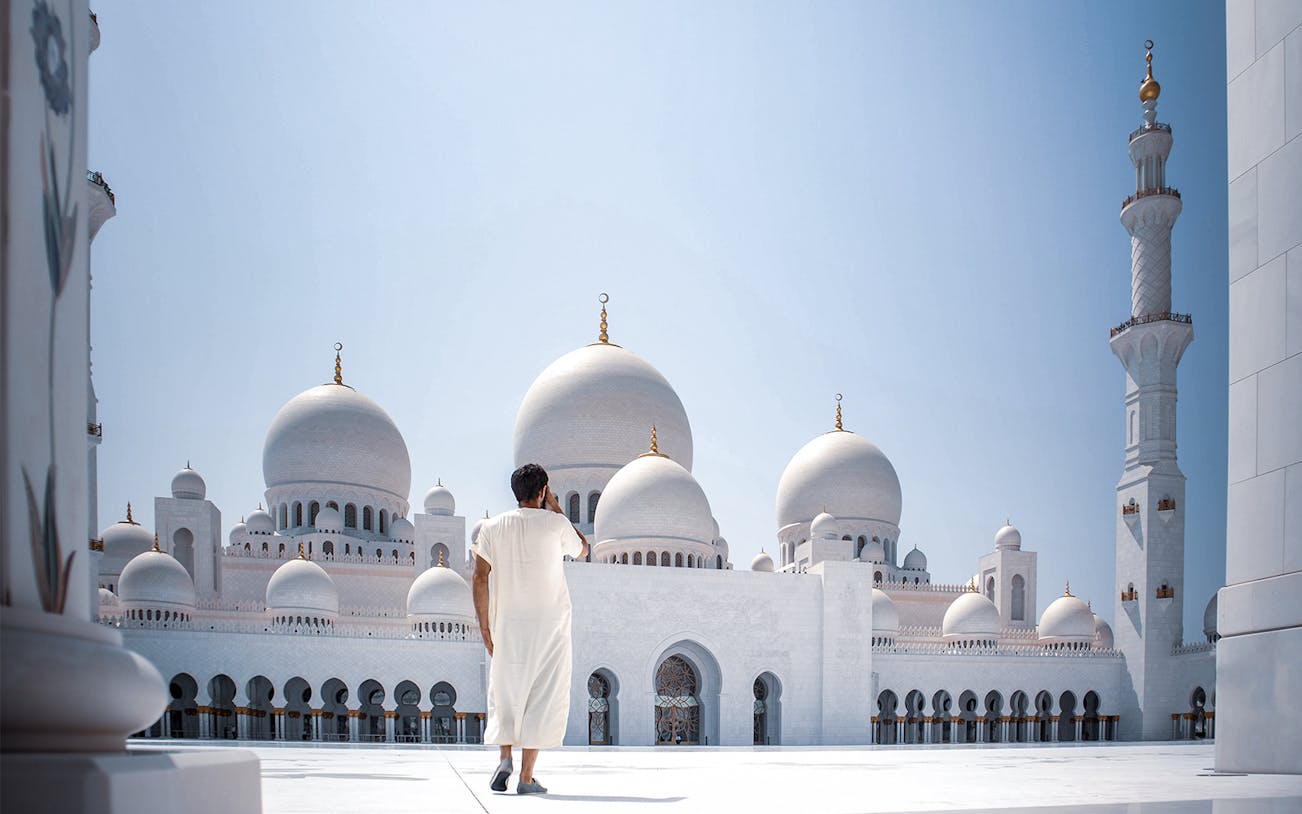 Person walking towards Sheikh Zayed Grand Mosque in Abu Dhabi, Explore The Emirates.