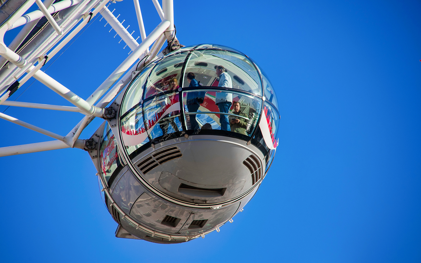London Eye capsule with passengers against a clear blue sky.