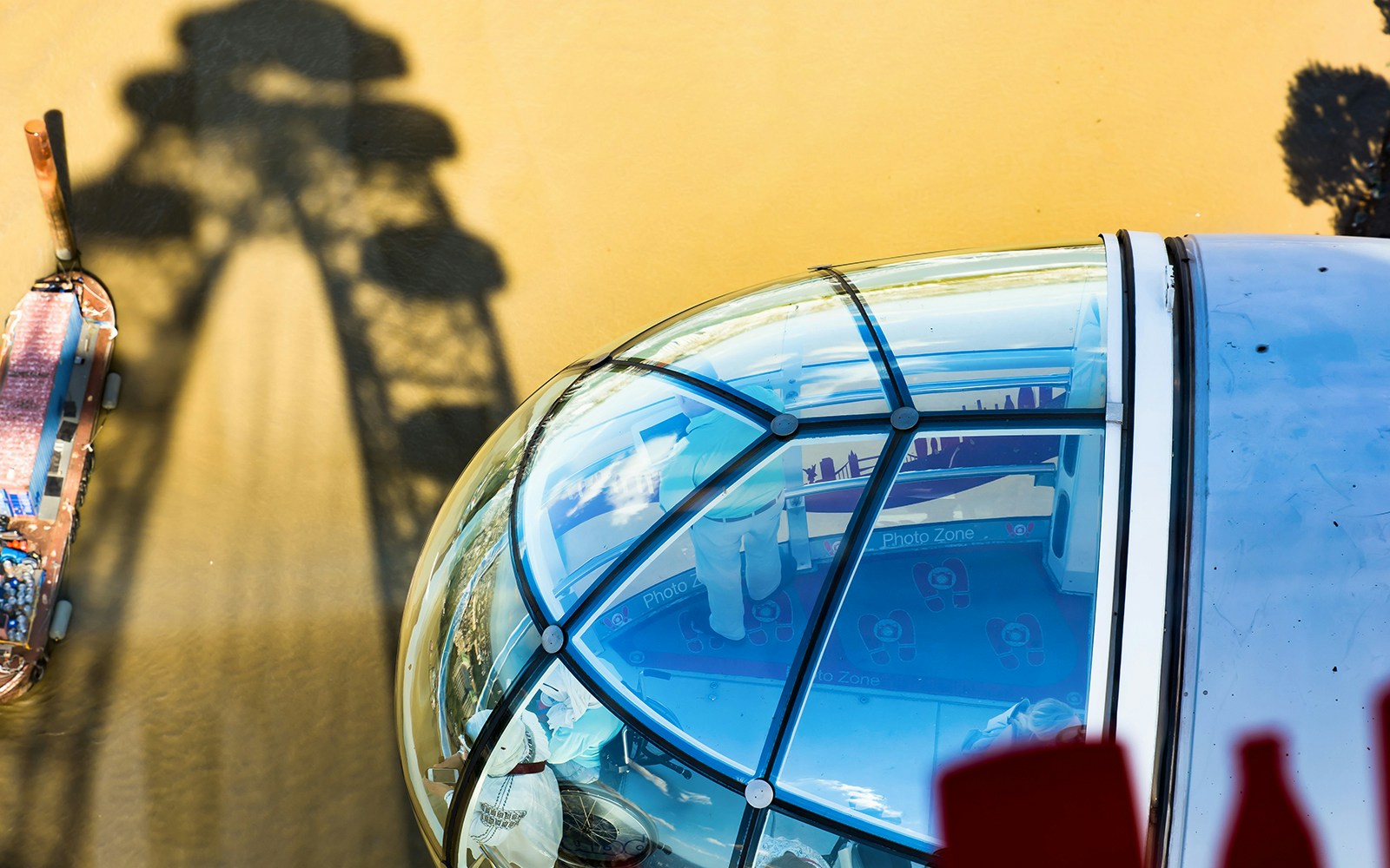 London double-decker bus near Tower of London with view of Coca-Cola London Eye in background.