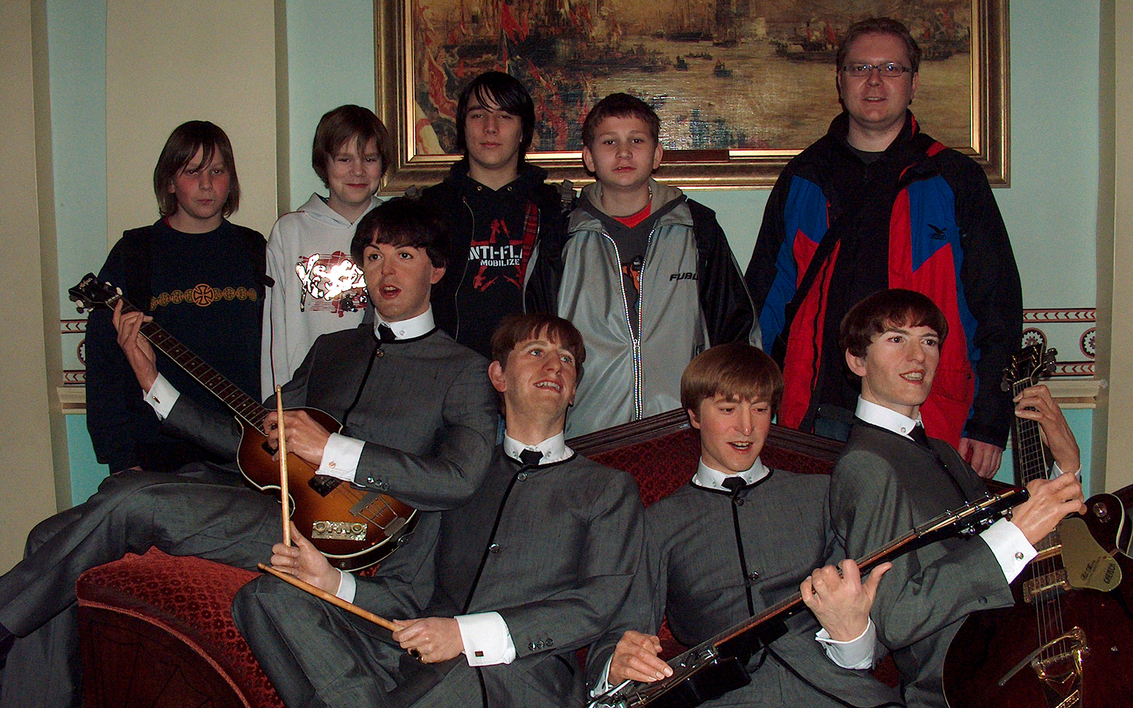 Wax figures of a famous band at Madame Tussauds London with visitors in the background.