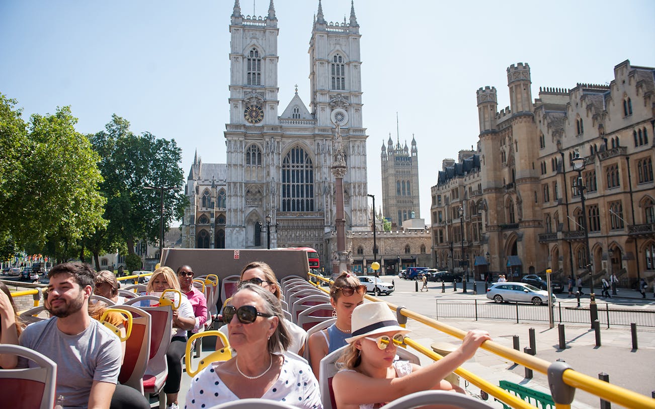 Open-top bus tour in London passing Westminster Abbey.