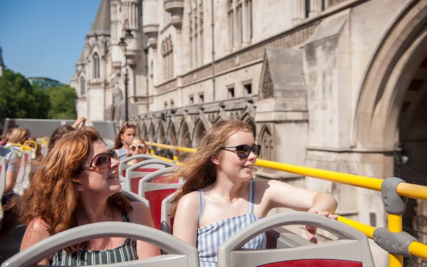 Open-top bus tour in London passing historic architecture.