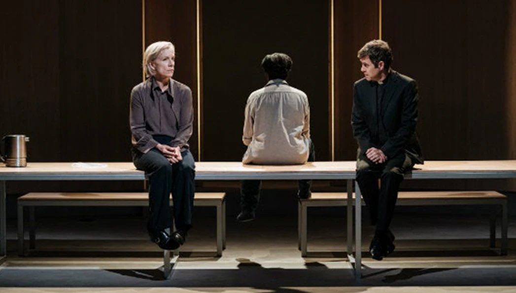 Three people seated on a bench in a dramatic scene from "The Doctor" play.