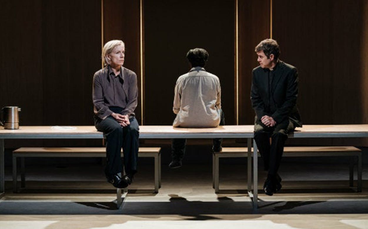 Three people seated on a bench in a dramatic scene from "The Doctor" play.