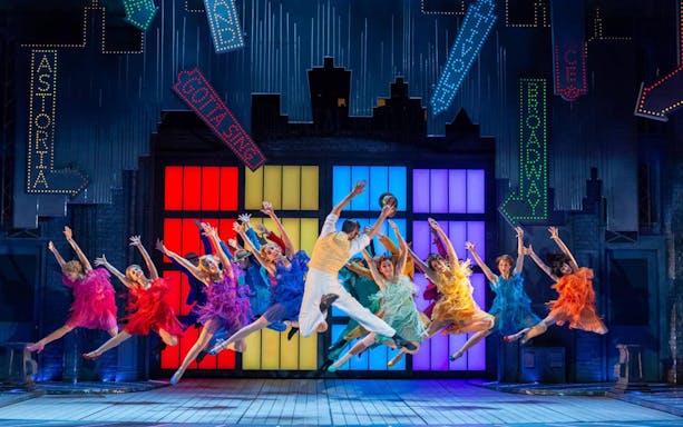 Performers dancing energetically on stage in "Singin' In The Rain" musical.