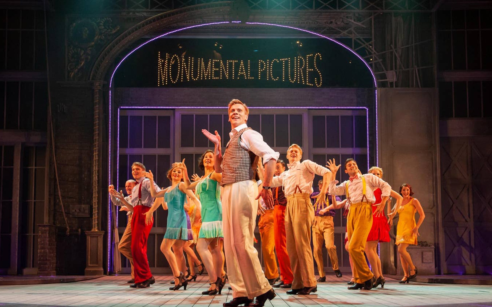 Performers dancing on stage in a scene from "Singin' In The Rain" musical.