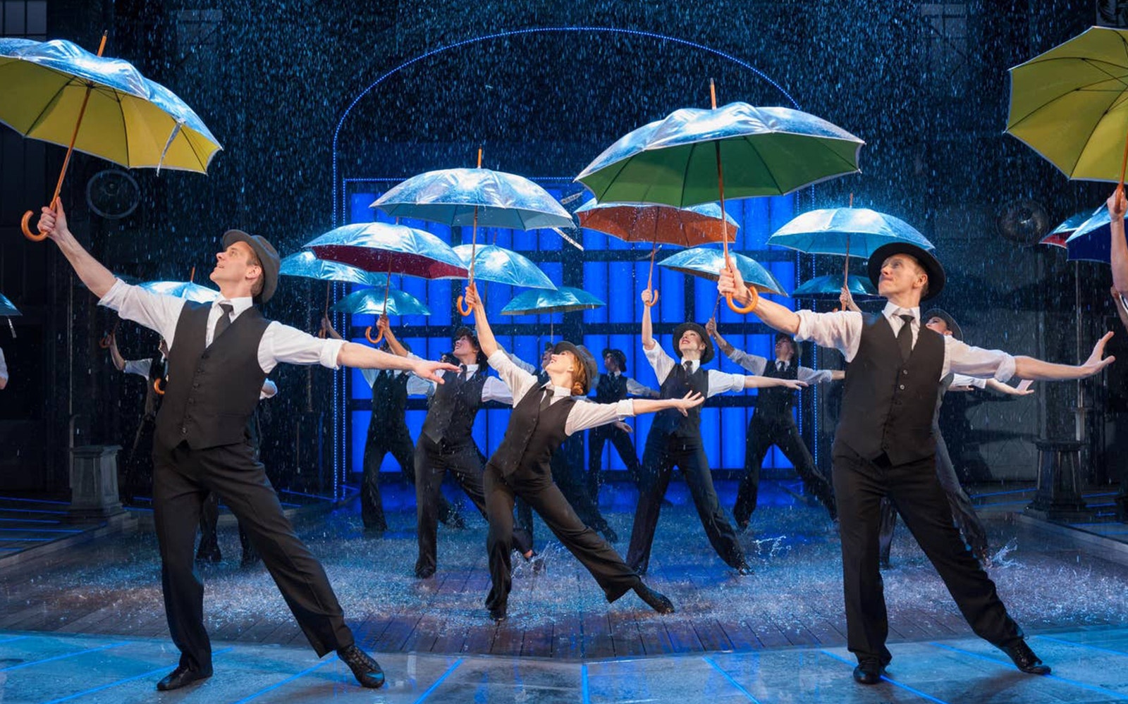 Performers dancing with umbrellas in a "Singin' In The Rain" stage show.