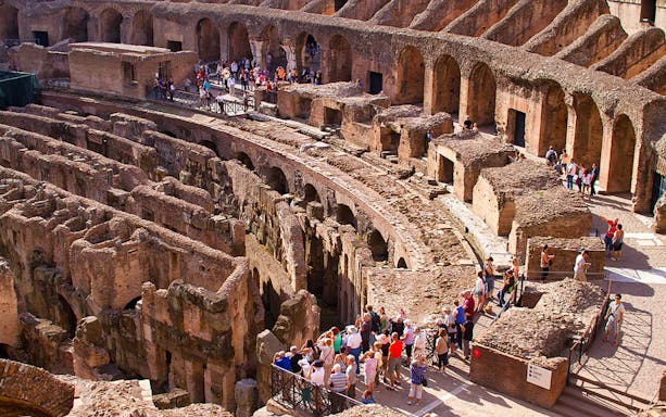 Colosseum interior with tourists exploring ancient ruins, Rome.