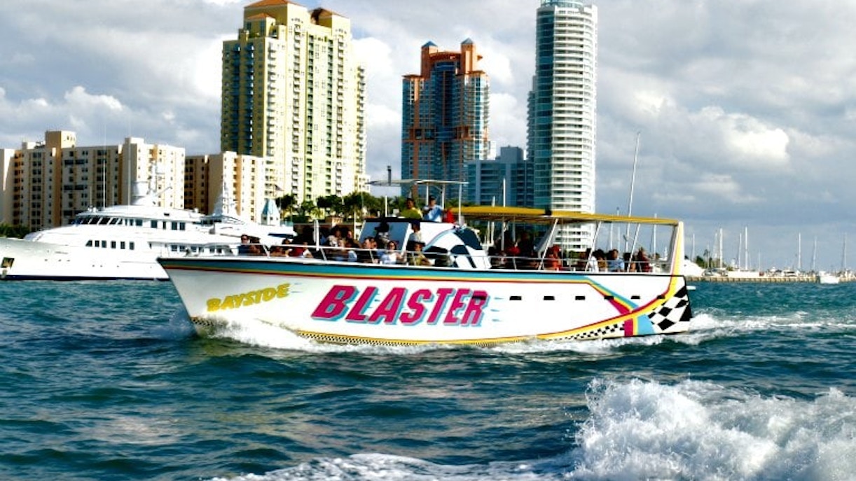 Speedboat cruising through Miami's Biscayne Bay with city skyline in the background.