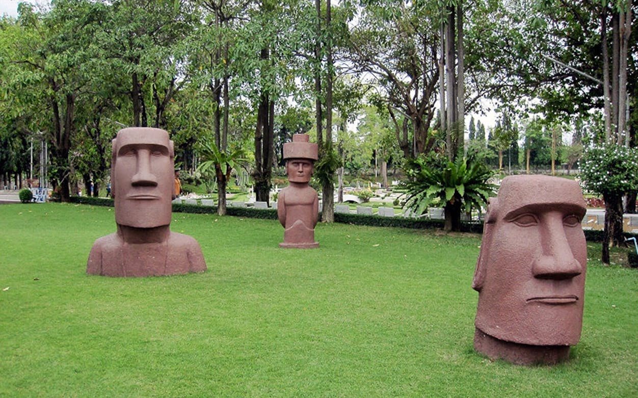 Mini Siam park in Pattaya featuring replica Moai statues on green lawn.