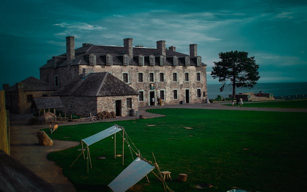 Historic stone building at Old Fort Niagara, USA, with Lake Ontario in the background.