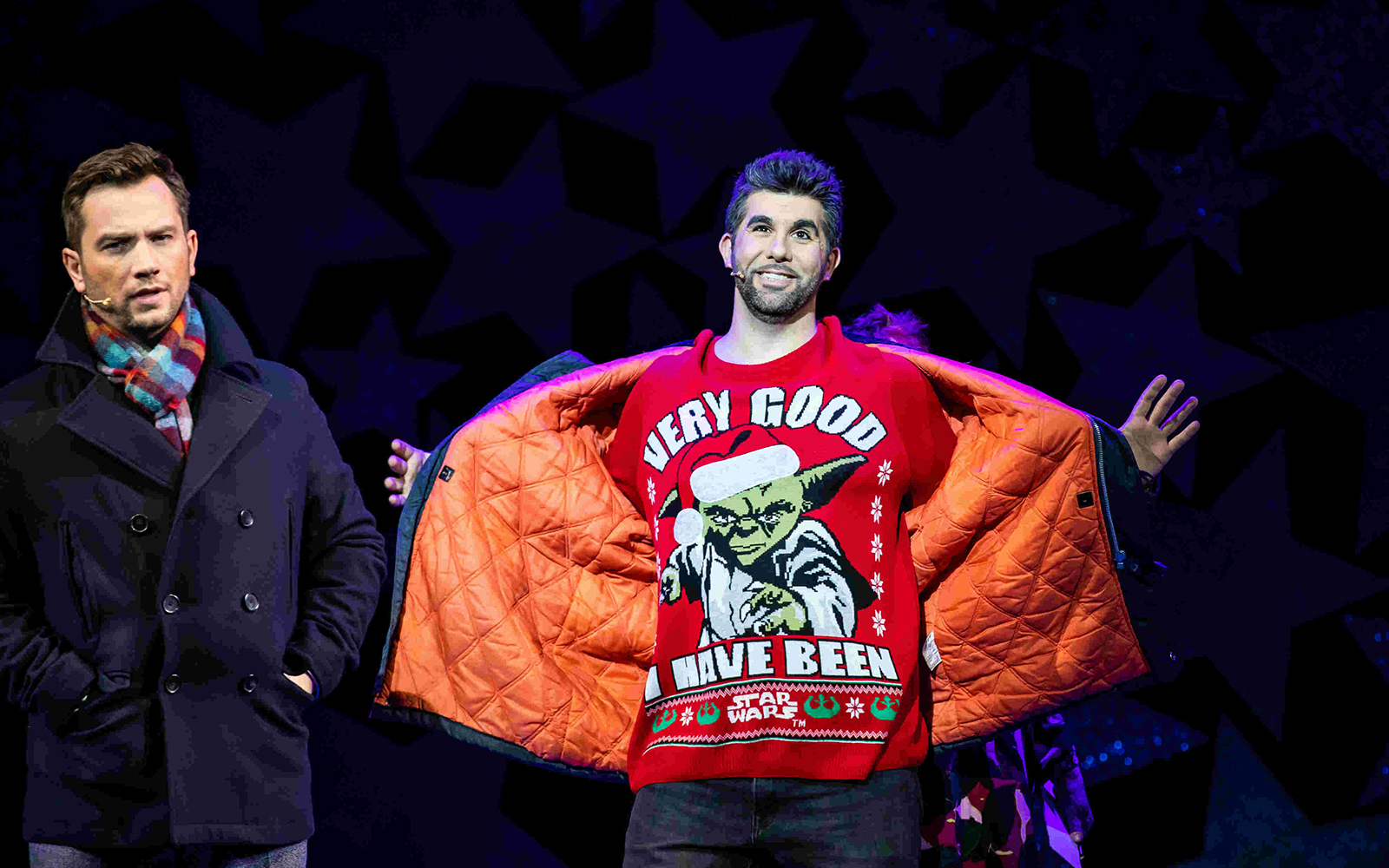 Two performers on stage during Nativity! The Musical, one wearing a festive sweater.