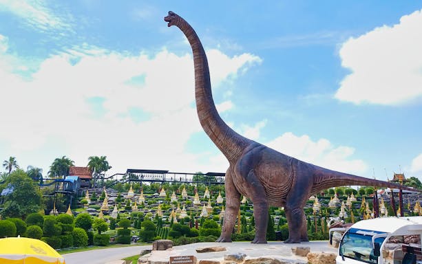 Brachiosaurus statue at Nong Nooch Tropical Garden, Thailand, with landscaped gardens in the background.