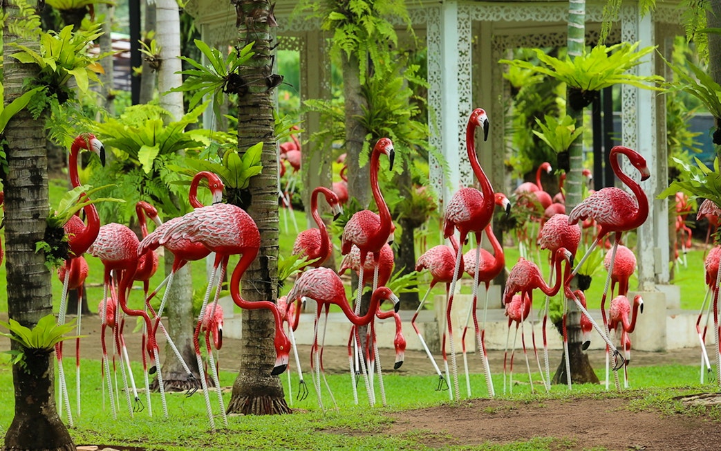 Flamingo sculptures among palm trees at Nong Nooch Tropical Garden.