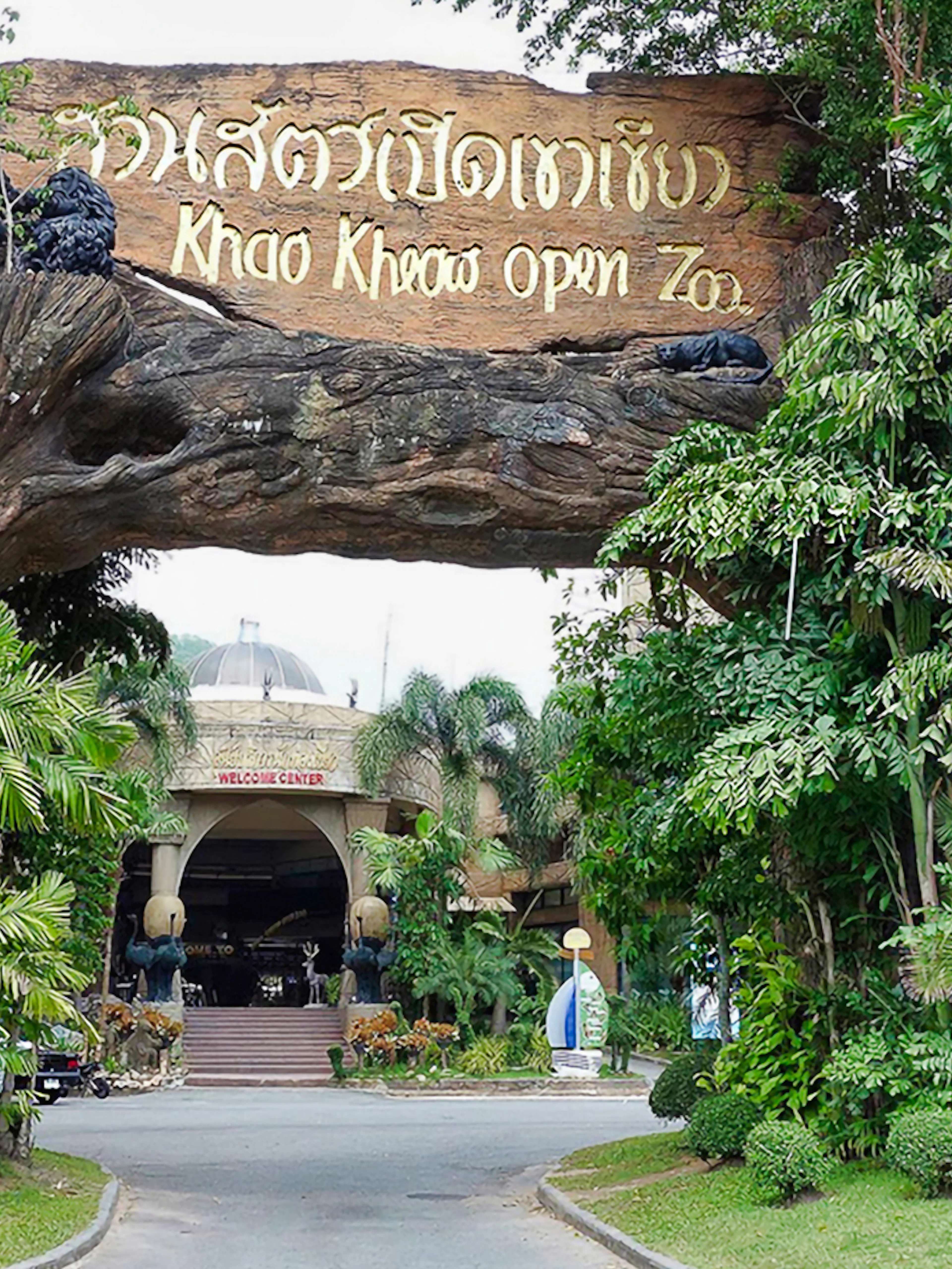 Entrance to Khao Kheow Open Zoo surrounded by lush greenery and a large wooden sign.