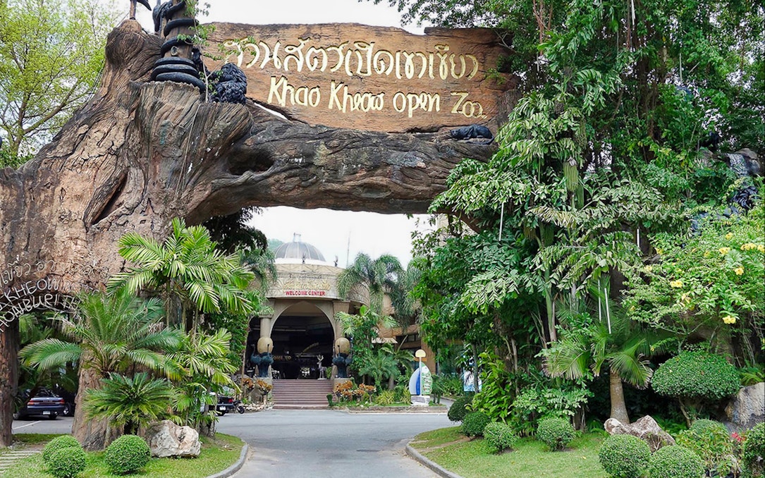 Entrance to Khao Kheow Open Zoo surrounded by lush greenery and a large wooden sign.