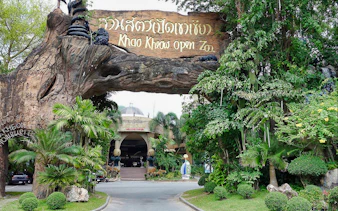 Entrance to Khao Kheow Open Zoo surrounded by lush greenery and a large wooden sign.