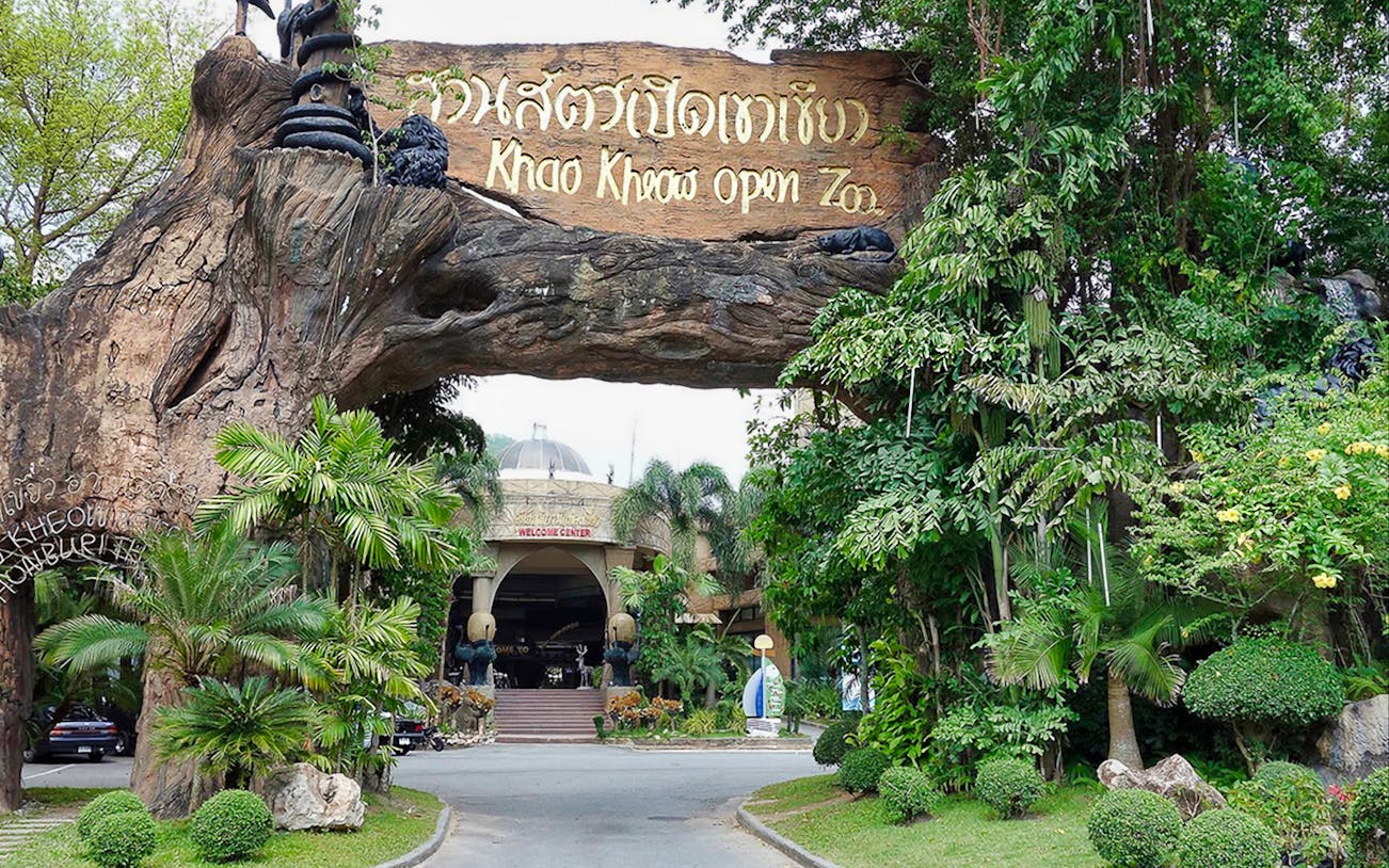 Entrance to Khao Kheow Open Zoo surrounded by lush greenery and a large wooden sign.