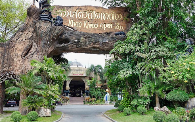 Entrance to Khao Kheow Open Zoo surrounded by lush greenery and a large wooden sign.