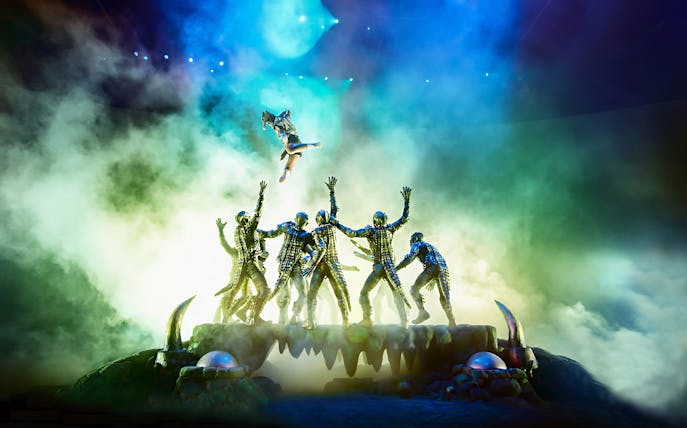 Performers in elaborate costumes during a KAAN Show act with dramatic lighting.