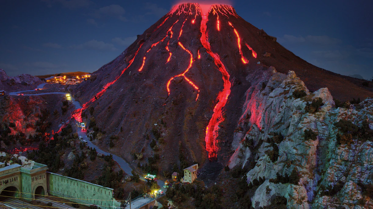 Miniatur Wunderland model of a volcano with glowing lava flows at night.