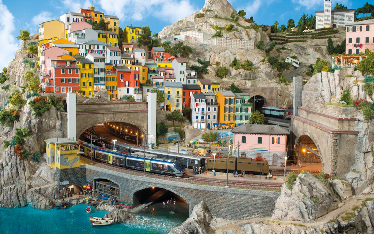 Miniatur Wunderland model of colorful hillside village with trains and tunnels.