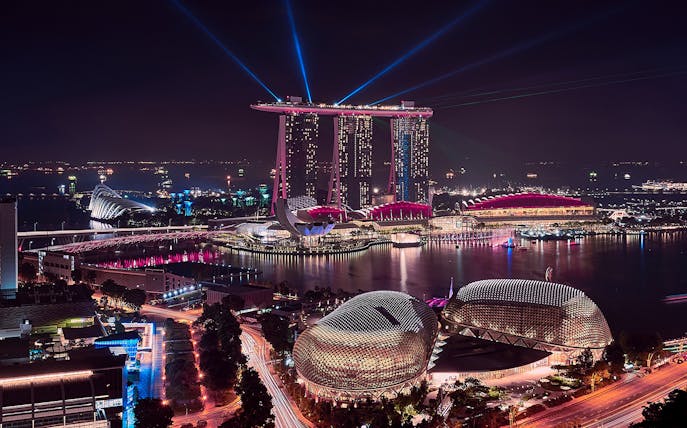 Singapore skyline at night featuring Marina Bay Sands and Esplanade during a river cruise.