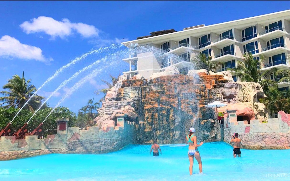 Visitors enjoying the wave pool at Splash Jungle Waterpark with water jets and rock formations.
