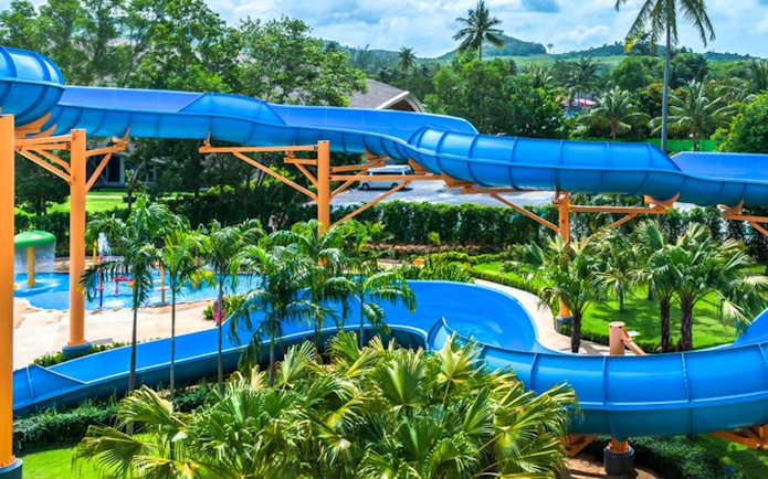 Blue water slide at Splash Jungle Waterpark surrounded by tropical greenery.