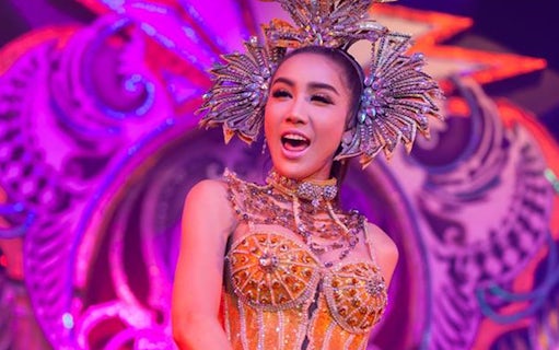 Performer in ornate costume at Aphrodite Cabaret Show, vibrant stage backdrop.