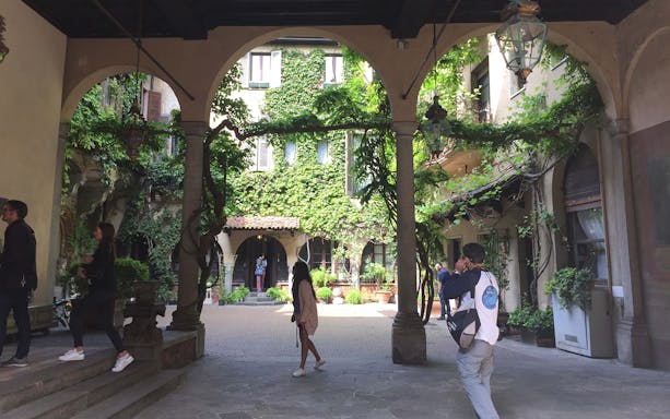 Courtyard with ivy-covered walls in Milan during guided tour.
