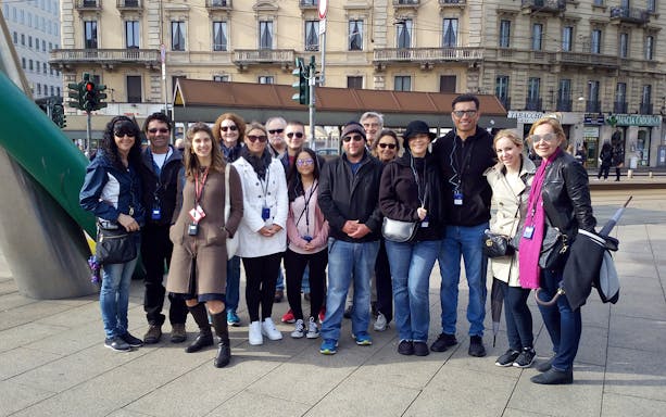 Group of tourists on Milan guided tour near historical building.