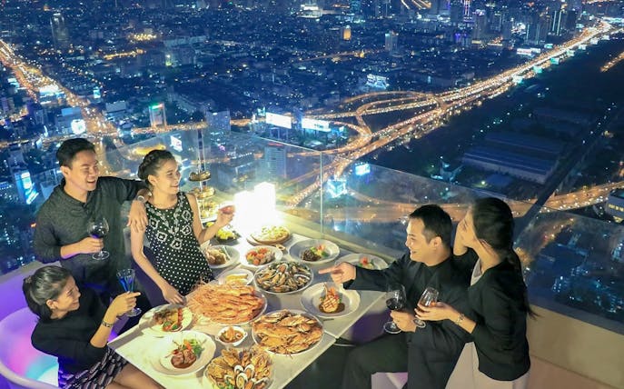 Dining experience at Baiyoke Floating Market Buffet, Baiyoke Sky Hotel's 75th floor, overlooking city lights.