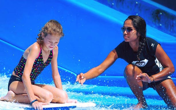 Child learning to surf with instructor at Surf House Phuket Kata Beach.