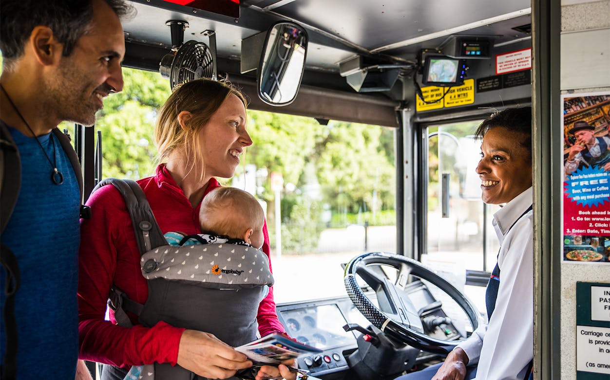 Tourists boarding Blue Mountain Explorer bus, greeted by driver.