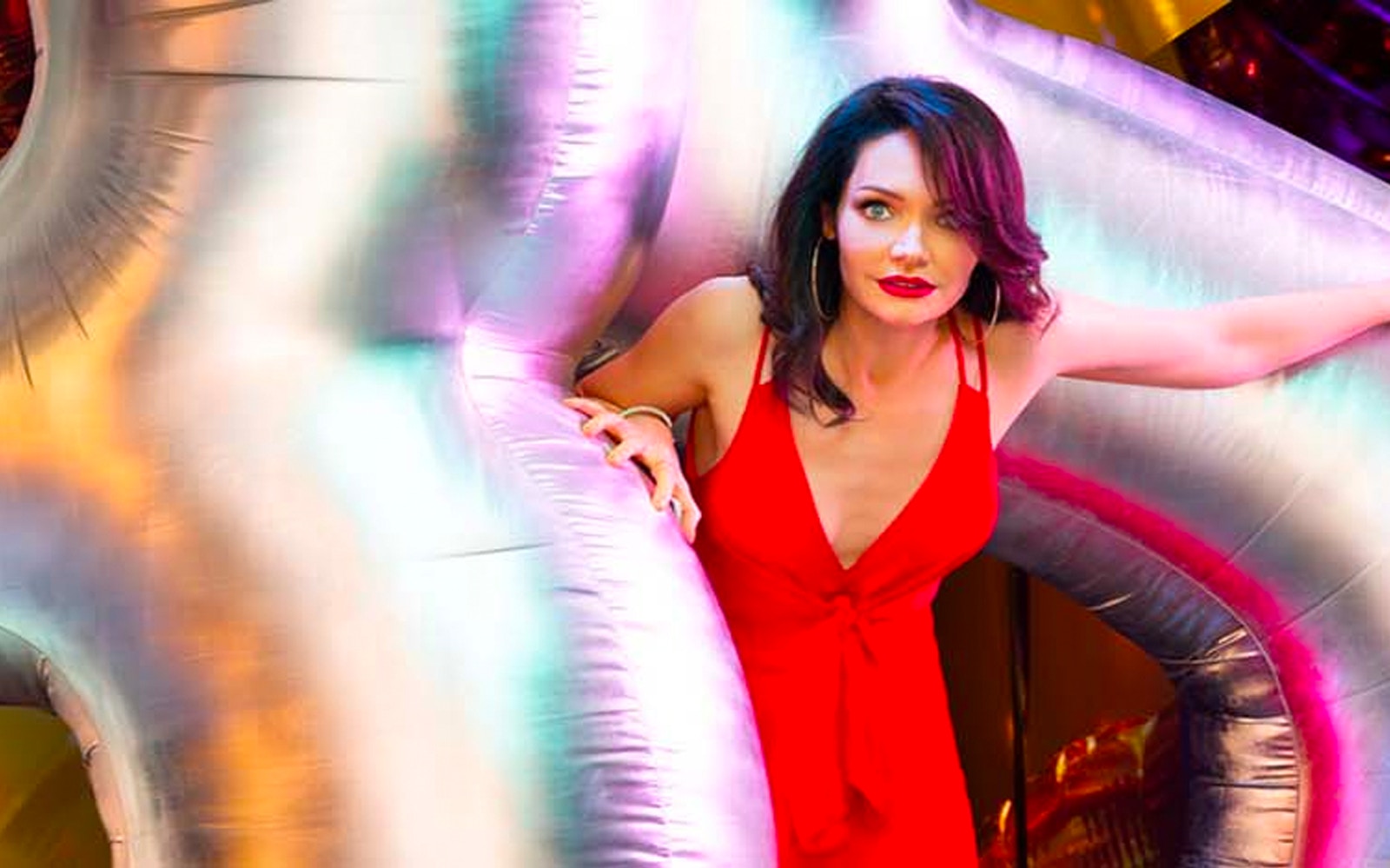 Woman in a red dress surrounded by colorful inflatable decorations.