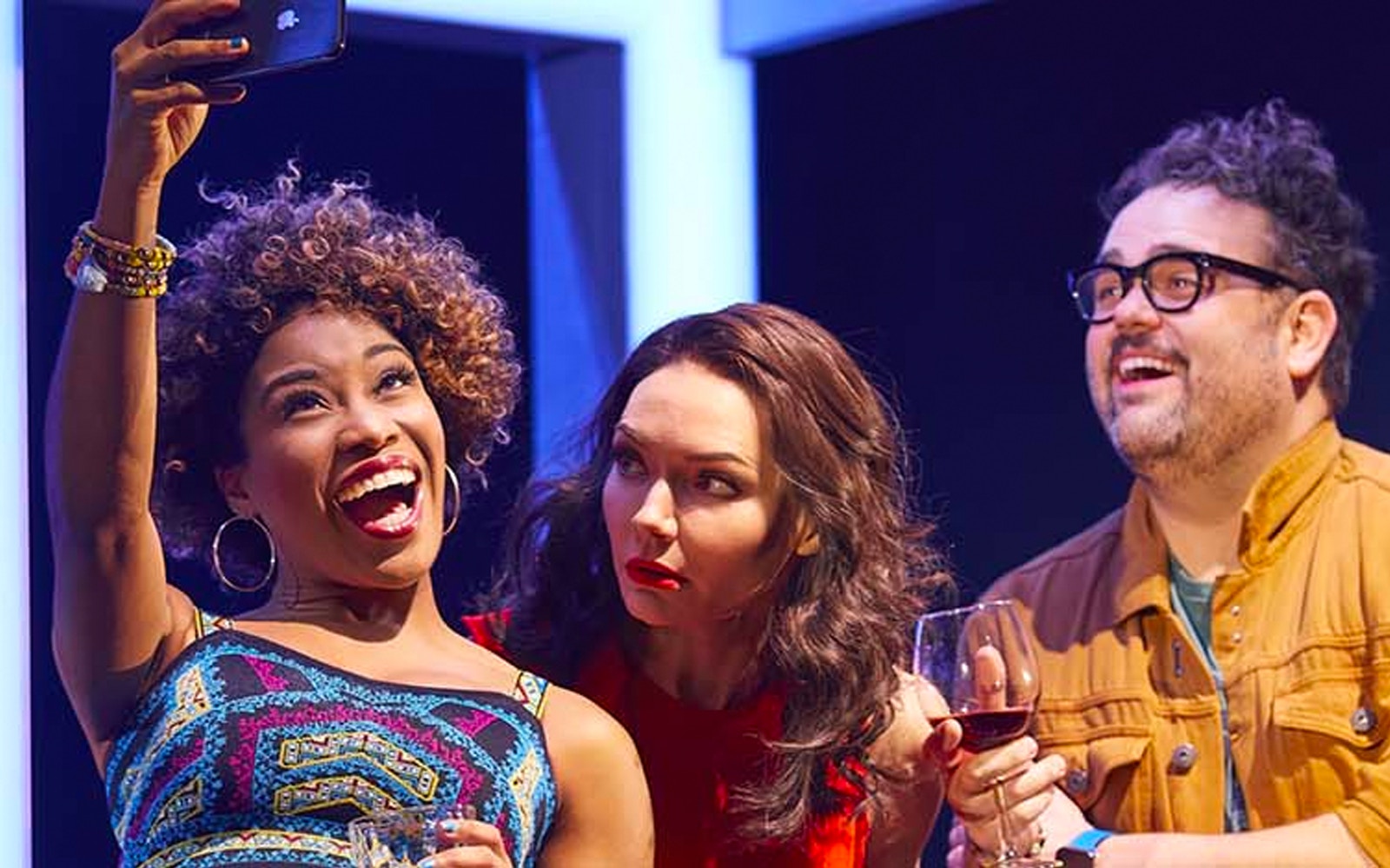Group of friends taking a selfie during a lively theater show.