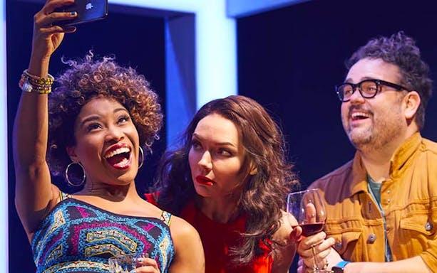 Group of friends taking a selfie during a lively theater show.