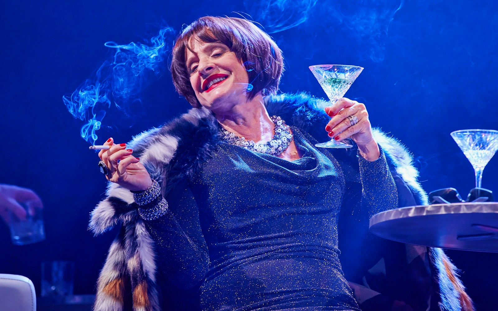 Elegant woman enjoying a drink and smoking at a glamorous event.