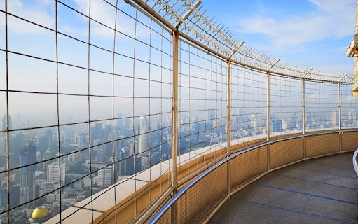 Baiyoke Sky Hotel observation deck view of Bangkok skyline through safety fence.