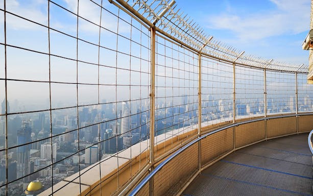 Baiyoke Sky Hotel observation deck view of Bangkok skyline through safety fence.