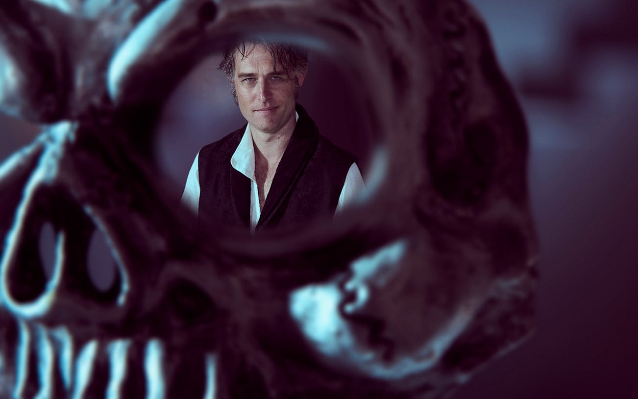 Man in period costume framed by a skull, related to Don Giovanni.