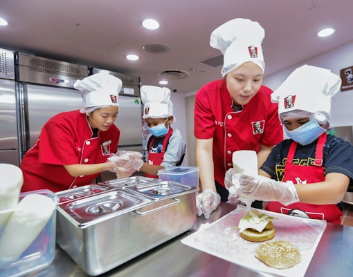 Children learning to make burgers at KidZania kitchen experience.